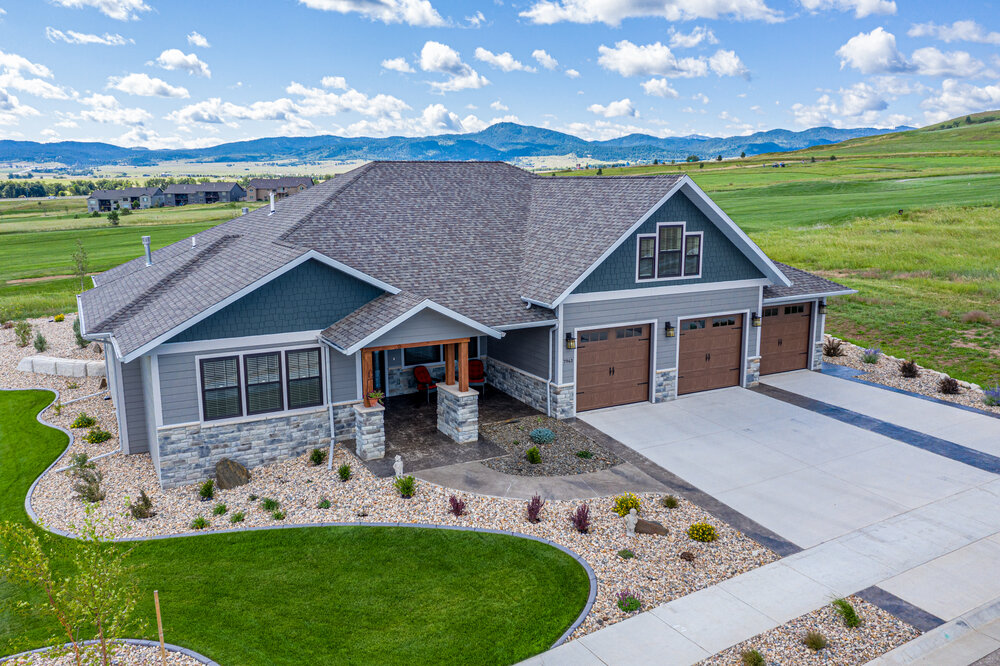 Front view of Elkhorn Ridge Estates custom home with green prairie and blue sky backdrop.