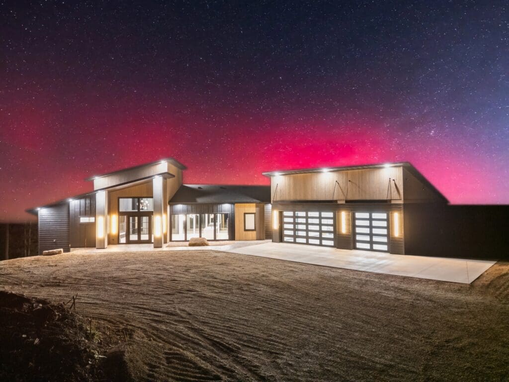 Custom luxury home built by Legacy Custom Homes & Design at 11246 Paradise Gulch Loop in Lead, South Dakota, featuring modern architecture, expansive garage, and scenic Black Hills views at night.