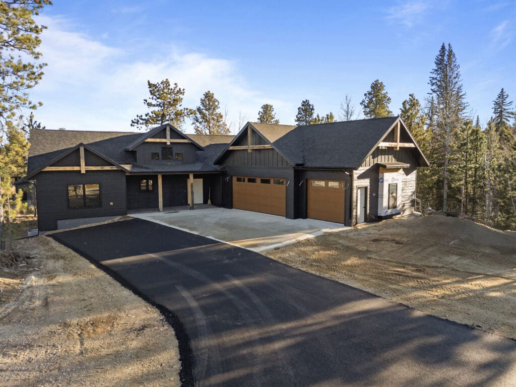 Custom Black Hills home built by Legacy Custom Homes & Design at 21306 Embers Way in Lead, South Dakota, featuring modern mountain architecture, three-car garage, and wooded surroundings.