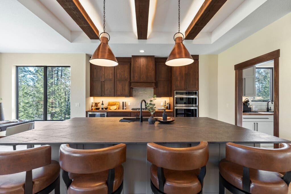 Custom kitchen in a home built by Legacy Custom Homes & Design at Lead Country Club in Lead, SD, featuring wood cabinetry, large island, and exposed beam ceiling.