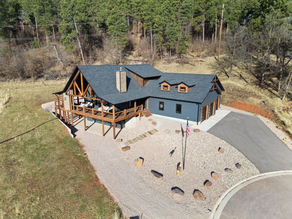 Custom home built by Legacy Custom Homes & Design in Apple Springs at Boulder Canyon, Sturgis, SD, featuring a large deck, wooded lot, and modern rustic design.