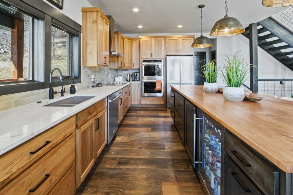 Luxury custom kitchen built by Legacy Custom Homes & Design in Apple Springs, featuring custom wood cabinetry, oversized island, quartz countertops, premium appliances, and modern mountain-home design.